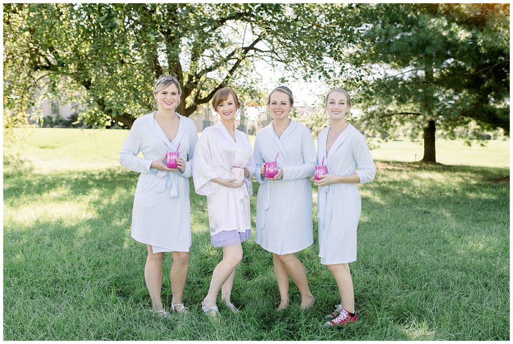 Bride and bridesmaids stand together in robes as they get ready for the wedding