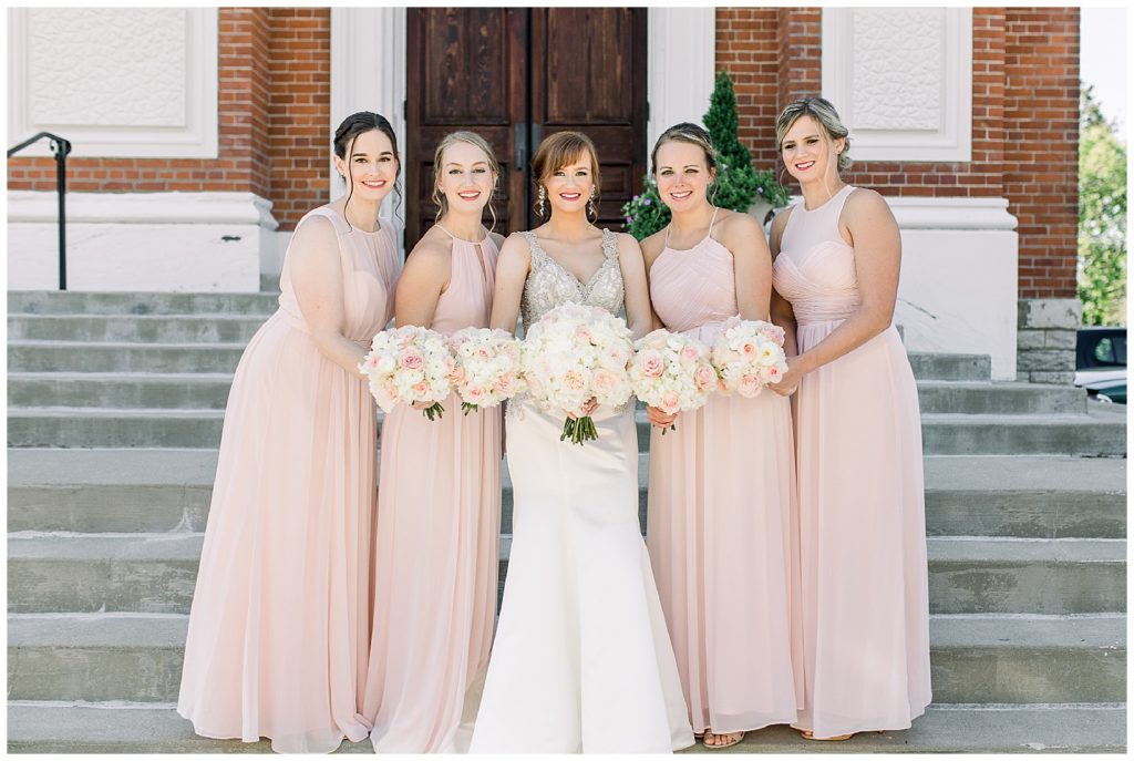 Bridal party standing on the front steps of the venue