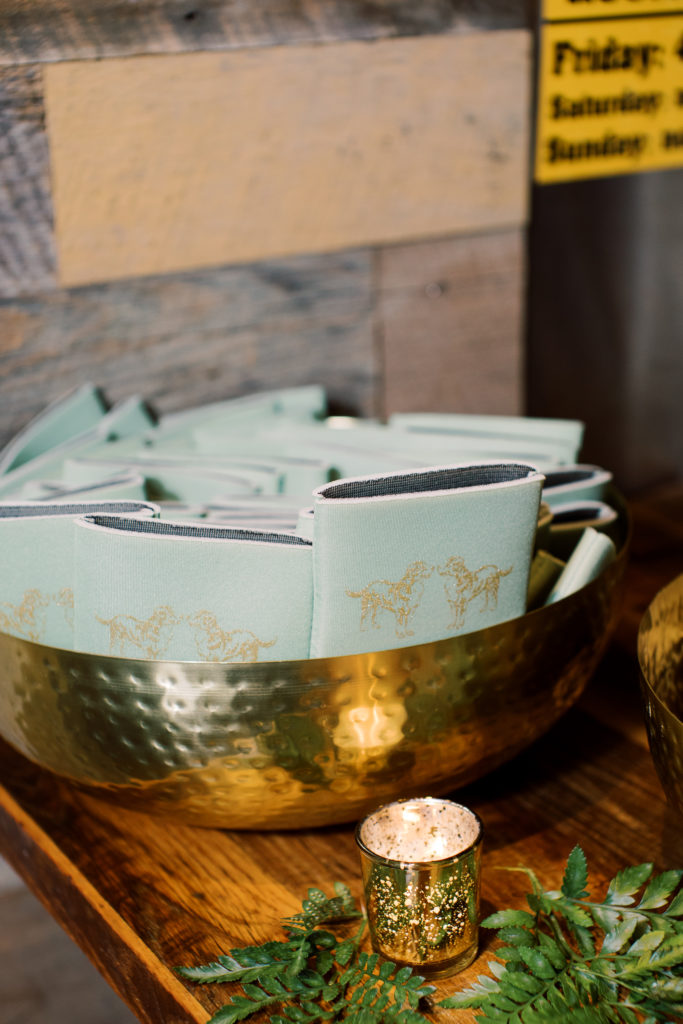 Close up photo of koozies with a dog screen print sitting in a bowl at the bar of a wedding reception